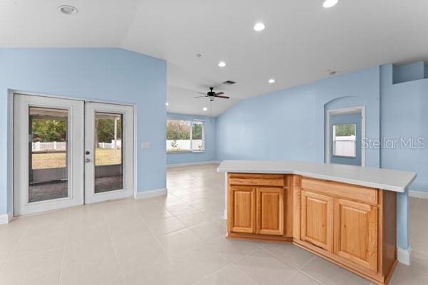 kitchen with french doors, vaulted ceiling, ceiling fan, light tile patterned floors, and a kitchen island