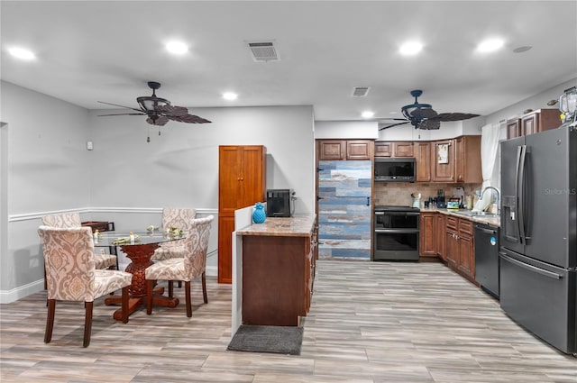 kitchen with sink, ceiling fan, appliances with stainless steel finishes, light stone counters, and decorative backsplash