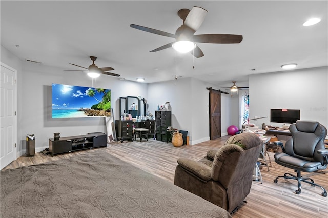 living room with a barn door, ceiling fan, and light wood-type flooring