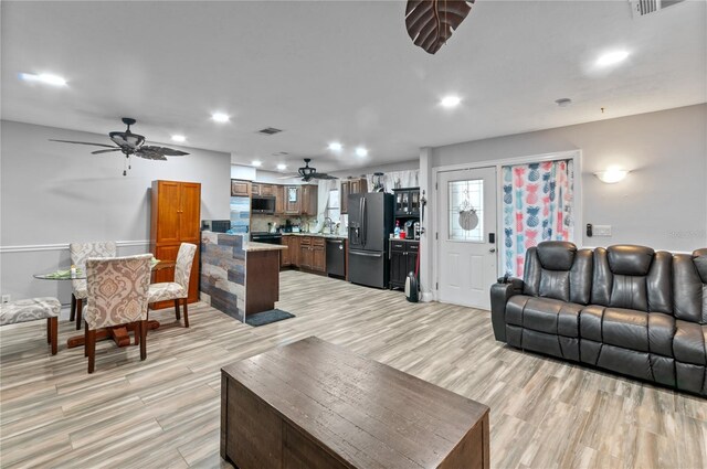 living room featuring ceiling fan, sink, and light hardwood / wood-style floors