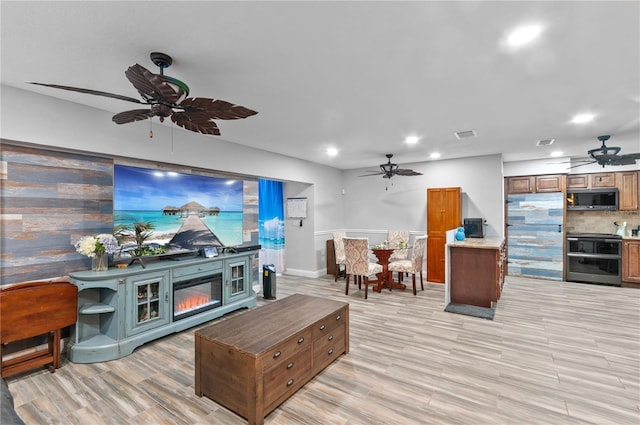 living room featuring a fireplace, light hardwood / wood-style flooring, and ceiling fan