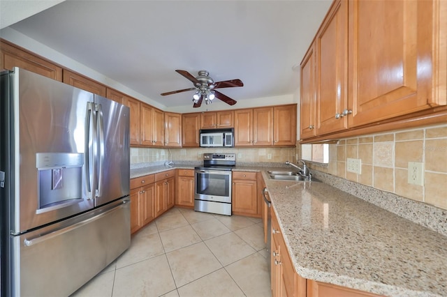 kitchen with sink, ceiling fan, appliances with stainless steel finishes, light tile patterned flooring, and light stone counters