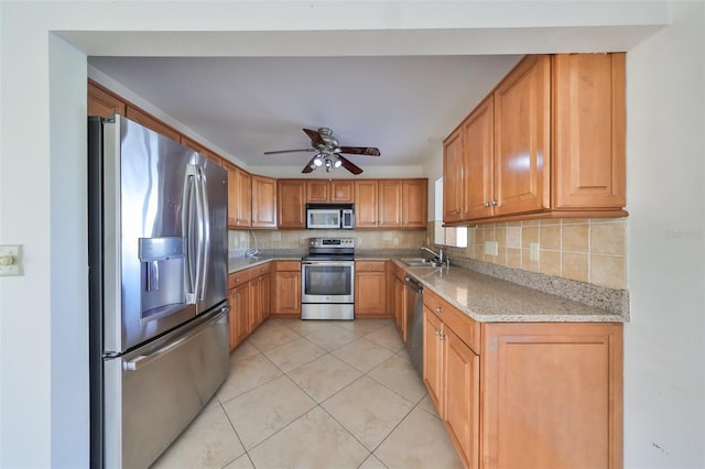 kitchen with sink, ceiling fan, tasteful backsplash, light stone counters, and stainless steel appliances