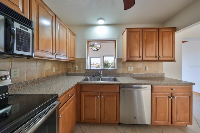 kitchen with sink, light tile patterned flooring, stainless steel appliances, and stone countertops