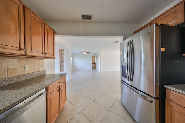 kitchen featuring ceiling fan, stainless steel appliances, tasteful backsplash, light stone counters, and light tile patterned flooring