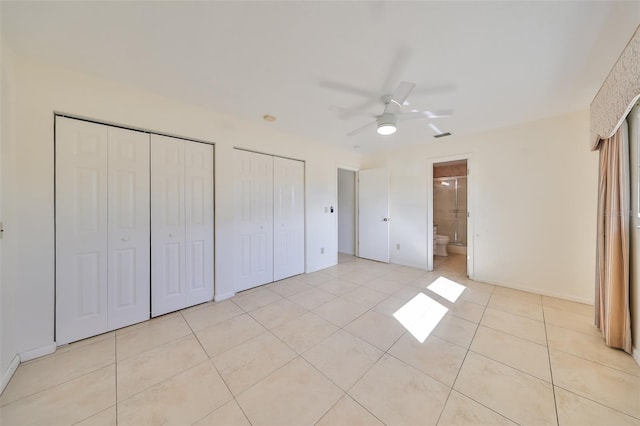 unfurnished bedroom featuring ceiling fan, multiple closets, light tile patterned floors, and ensuite bath