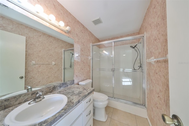 bathroom featuring toilet, vanity, tile patterned floors, and a shower with door