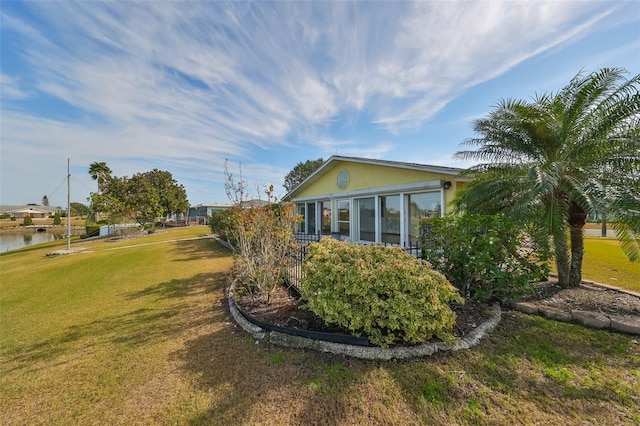 view of side of home featuring a lawn and a water view