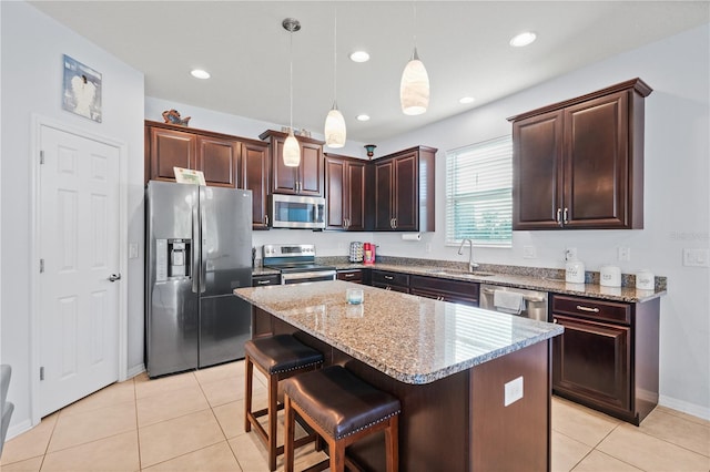 kitchen with appliances with stainless steel finishes, sink, light tile patterned floors, pendant lighting, and a center island