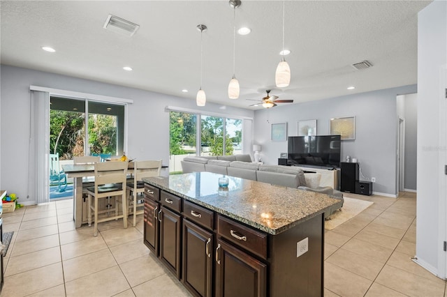 kitchen featuring pendant lighting, a center island, light tile patterned floors, and ceiling fan