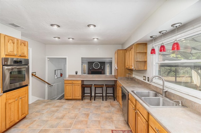 kitchen featuring sink, light tile patterned floors, stainless steel appliances, and decorative light fixtures