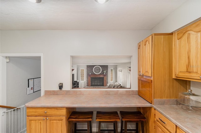 kitchen featuring light brown cabinetry and a fireplace