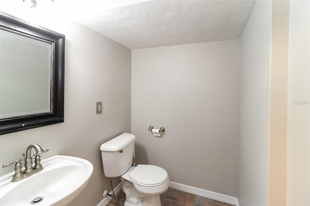 bathroom with tile patterned floors, a textured ceiling, toilet, and sink