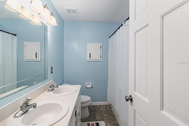 bathroom featuring tile patterned flooring, vanity, toilet, and a textured ceiling