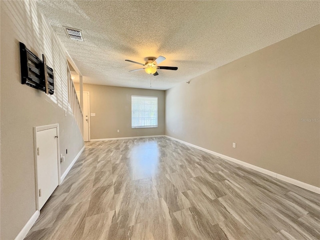 unfurnished living room with ceiling fan, light wood-type flooring, and a textured ceiling