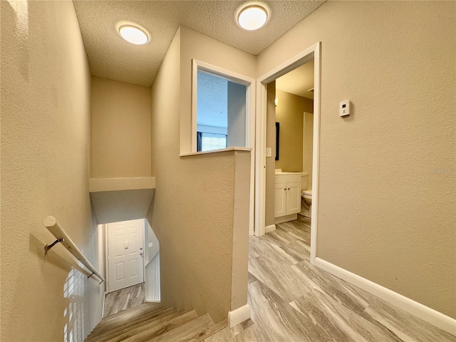 staircase featuring a textured ceiling and hardwood / wood-style flooring