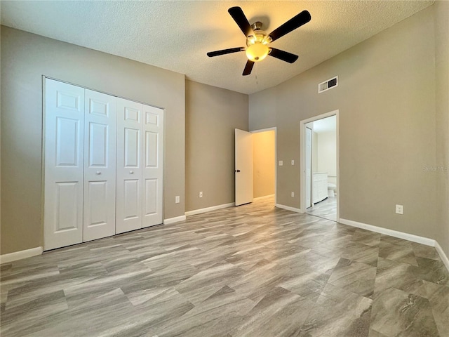 unfurnished bedroom with a textured ceiling, a closet, ensuite bath, and ceiling fan