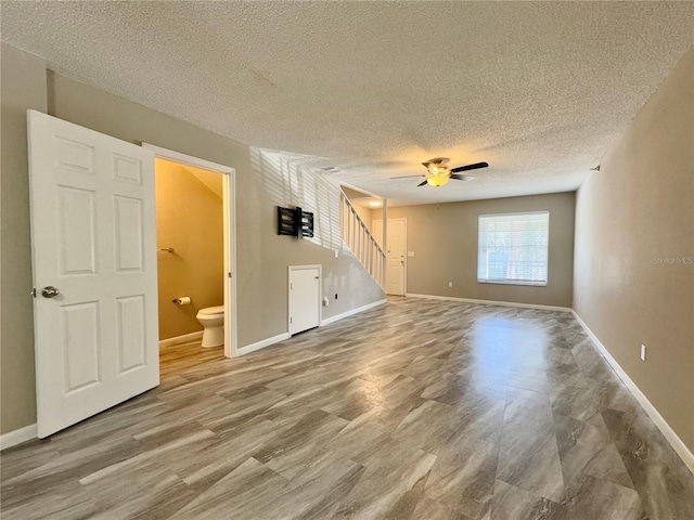 unfurnished living room featuring a textured ceiling, hardwood / wood-style flooring, and ceiling fan