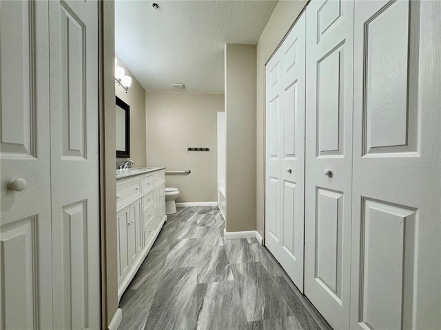 bathroom featuring vanity, a textured ceiling, and toilet