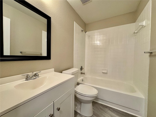 full bathroom with vanity, wood-type flooring, tiled shower / bath combo, and toilet