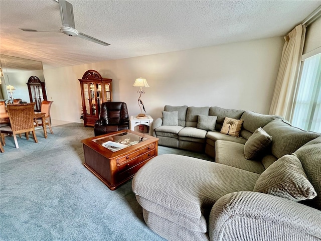 carpeted living room featuring a ceiling fan and a textured ceiling