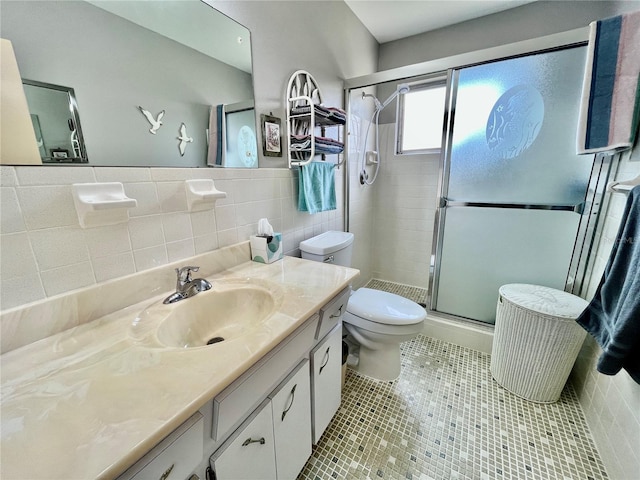 bathroom with tile patterned floors, toilet, a stall shower, tile walls, and vanity