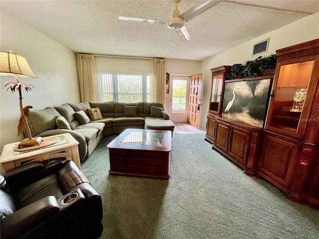 living room featuring visible vents, carpet, a ceiling fan, and a textured ceiling