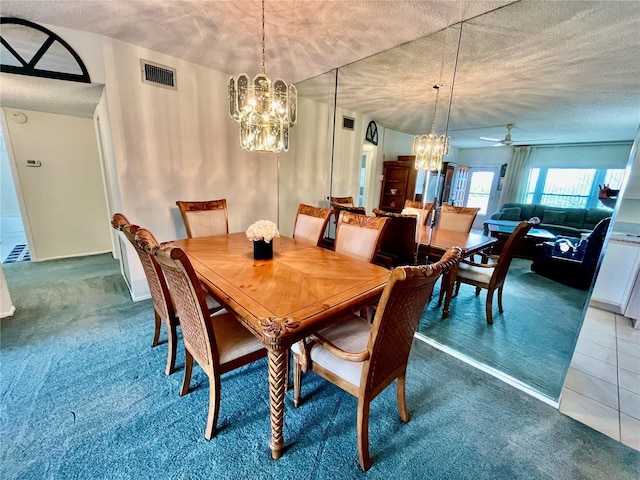 dining space featuring tile patterned floors, visible vents, ceiling fan with notable chandelier, a textured ceiling, and carpet