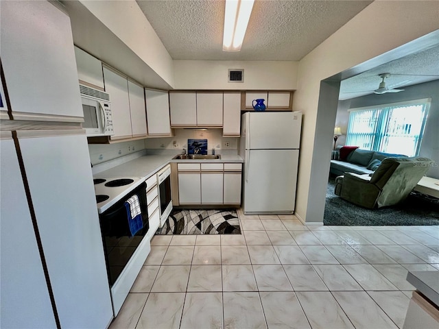 kitchen featuring visible vents, light countertops, light tile patterned flooring, white appliances, and a textured ceiling