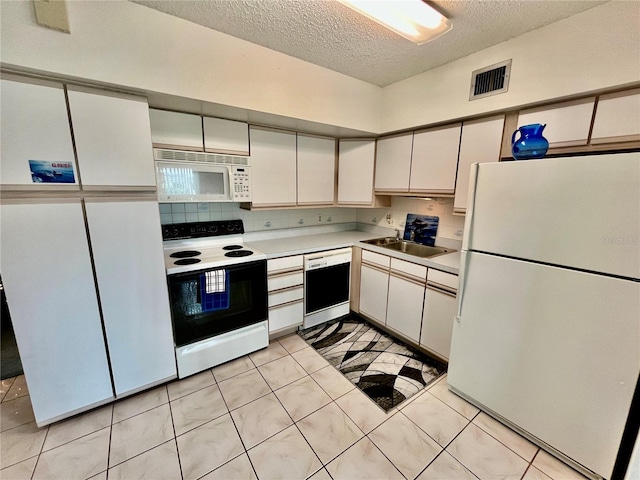 kitchen featuring white appliances, visible vents, a sink, light countertops, and a textured ceiling