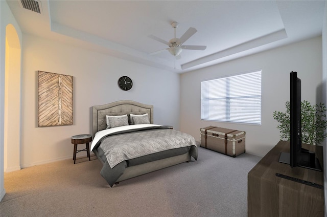 bedroom featuring ceiling fan, a raised ceiling, and light carpet