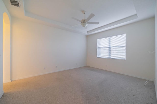 carpeted empty room featuring ceiling fan and a tray ceiling