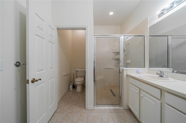 bathroom with tile patterned flooring, vanity, a shower with door, and toilet