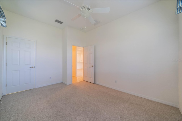 unfurnished bedroom with light colored carpet, ceiling fan, and a high ceiling