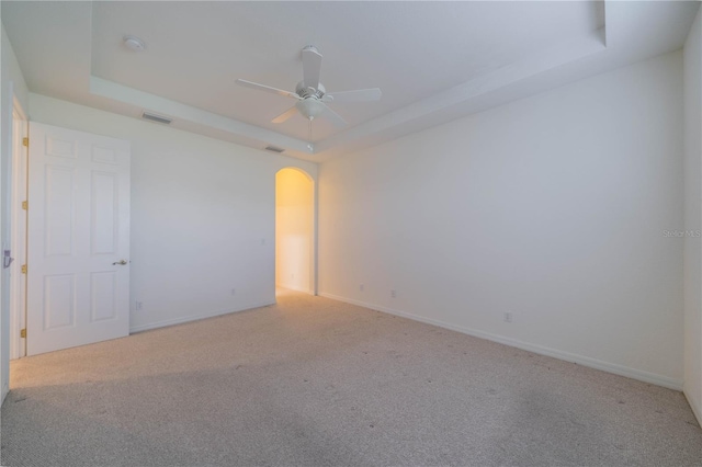 carpeted empty room with ceiling fan and a tray ceiling