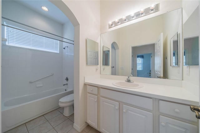 full bathroom with washtub / shower combination, toilet, tile patterned flooring, and a wealth of natural light