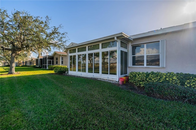 rear view of house with a sunroom and a lawn