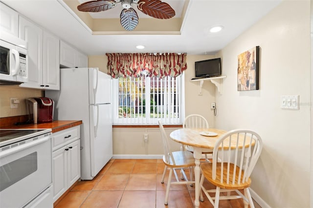 kitchen with white appliances, backsplash, ceiling fan, light tile patterned flooring, and white cabinetry