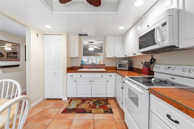 kitchen featuring white appliances, sink, light tile patterned floors, tasteful backsplash, and white cabinetry