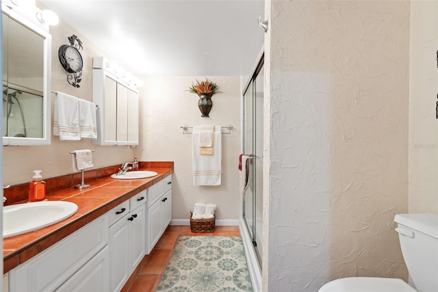 bathroom with tile patterned flooring, vanity, toilet, and a shower with door