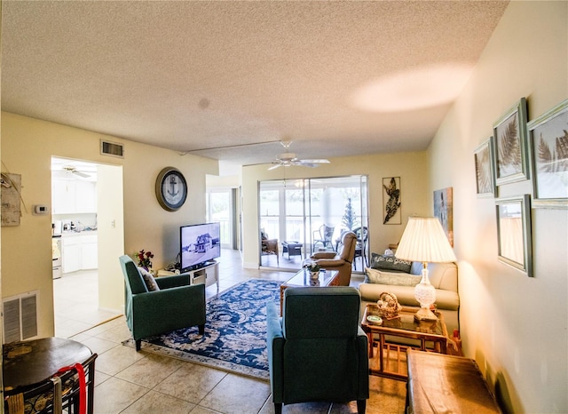 living room featuring ceiling fan, light tile patterned floors, and a textured ceiling