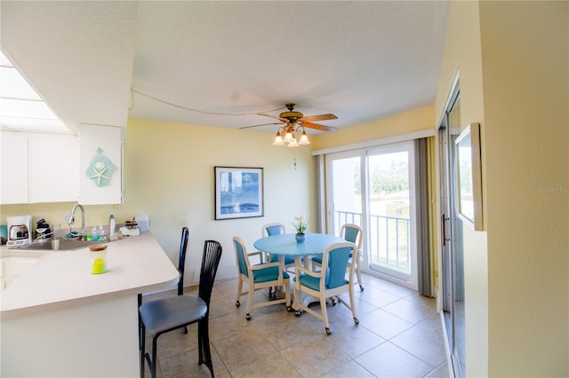 tiled dining space with ceiling fan, sink, and a textured ceiling