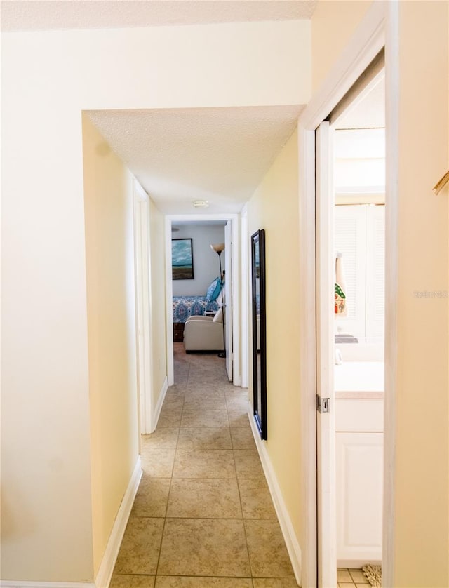 corridor featuring light tile patterned flooring and a textured ceiling