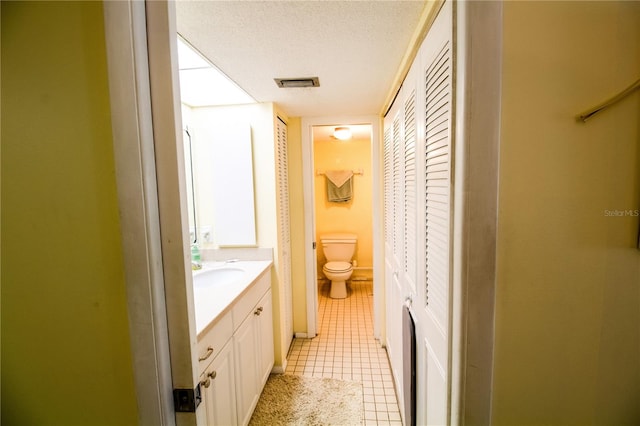 bathroom featuring tile patterned floors, vanity, a textured ceiling, and toilet