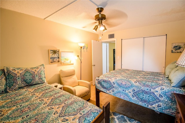 tiled bedroom featuring ceiling fan, a textured ceiling, and a closet