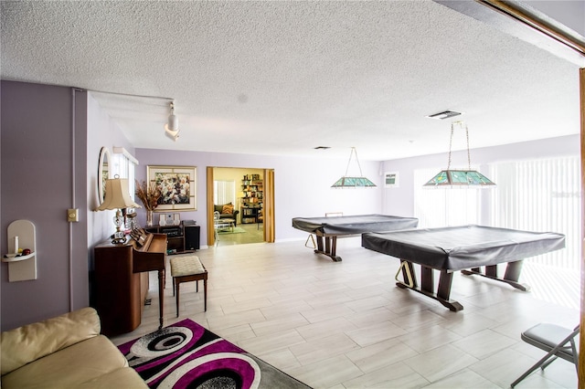 game room featuring rail lighting, a textured ceiling, and billiards