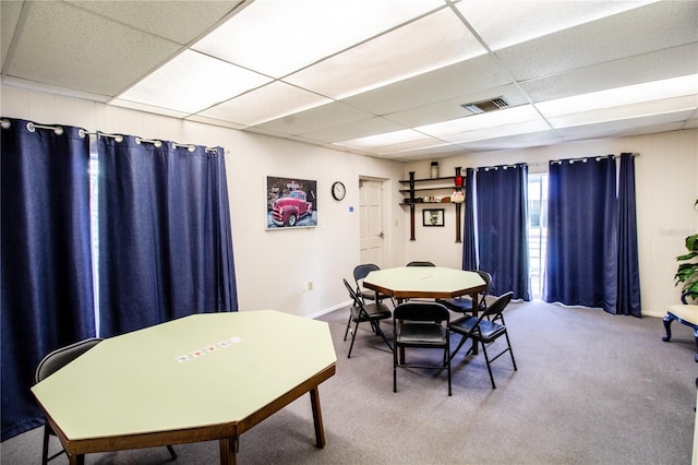 carpeted dining area with a paneled ceiling