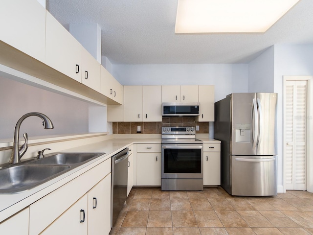 kitchen featuring sink, tasteful backsplash, a textured ceiling, light tile patterned floors, and appliances with stainless steel finishes