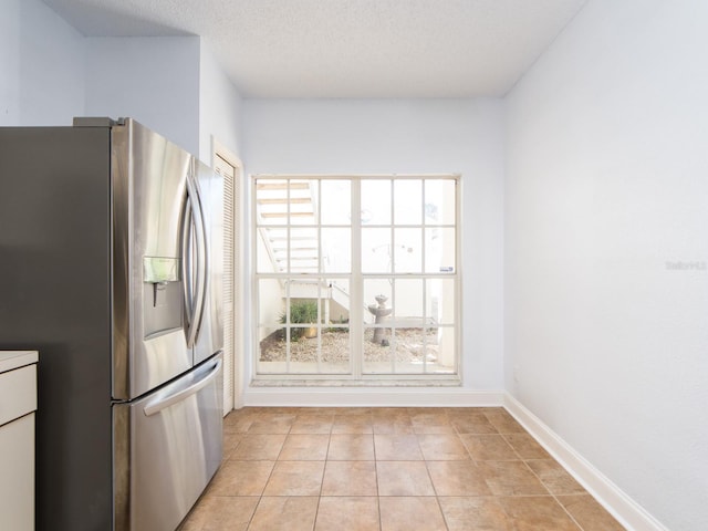 kitchen with stainless steel fridge with ice dispenser, a textured ceiling, and light tile patterned floors