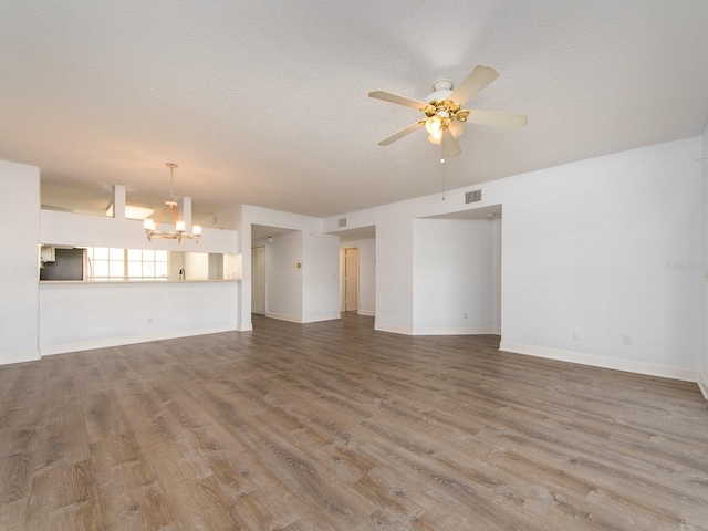 unfurnished living room with wood-type flooring, ceiling fan with notable chandelier, and a textured ceiling